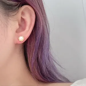 Detailed close-up of a vintage pearl earring with gold petal border on a model's ear