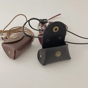 Detailed view of mini leather pouches in brown, black, and red with metal buttons