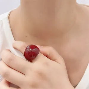 Macro shot of a chunky deep red resin ring showing glossy finish and smooth texture