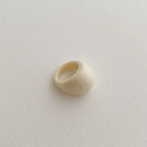 Macro detail of minimalist cream resin ring featuring a smooth polished glossy finish