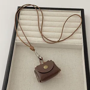 Close-up of brown leather mini coin pouch necklace with vintage bronze snap and lanyard