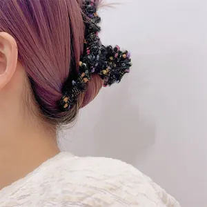 Detalle de la pinza para el pelo de tweed con hilos dorados en peinado púrpura