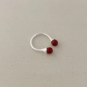 Detailed view of silver open ring featuring vibrant red agate beads on linen fabric