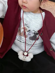 Close-up of child wearing a soft white plush bear neck pouch with a cute red mini hat