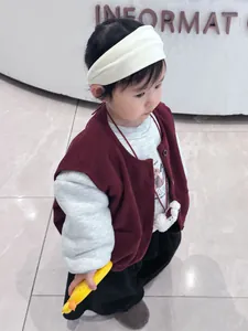 Detail of baby autumn outfit with grey sweatshirt, burgundy vest and banana accessory