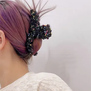 Detalle de una pinza para el pelo de tweed negro en cabello largo púrpura desde atrás