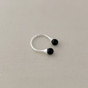 Close-up of a minimalist silver open ring featuring two polished black onyx beads