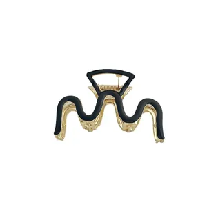 Elegante pinza per capelli in metallo dorato con motivo a onde nere su fondo bianco