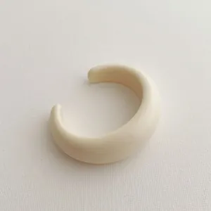 Detailed macro view of a creamy white resin open C-ring cuff with smooth polished finish