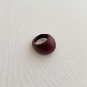 Close-up of a polished wine red resin bubble ring on a minimalist textured background