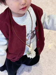 Detail of children's corduroy vest set with a cute plush bunny necklace accessory