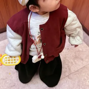 Detail view of child wearing dark red corduroy vest over a white teddy bear printed t-shirt