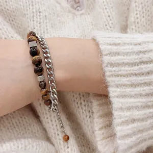 Zweilagiges Armband mit Tigerauge-Steinen und silberner Gliederkette auf weichem Strickärmel