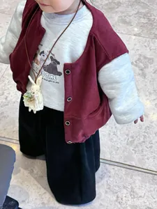 Detail showing toddler burgundy corduroy vest with cute rabbit plush toy necklace accent