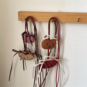 Detailweergave van mini pluche beer crossbodytassen in vier kleuren aan een rek