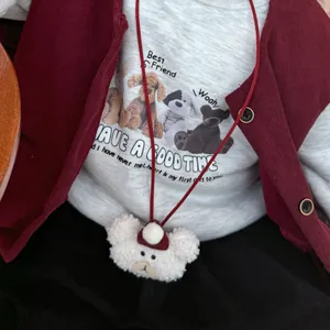 Cute white plush bear doll charm with red hat and cord on a child sweatshirt