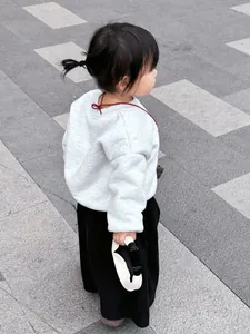 Detail of light gray long sleeve sweatshirt with red ribbon tie on a toddler outfit