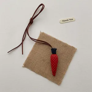 Detail of a handmade fabric carrot charm with red polka dots and a brown suede cord