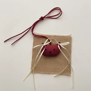 Donkerrode stoffen beer hanger met lintje op een rustieke achtergrond van jute