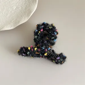 Detalle de la textura de tweed colorido y el tejido metálico afelpado de la pinza de pelo