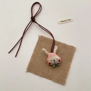 Close-up of handmade cloth rabbit pendant with pink strawberry fabric and jute base