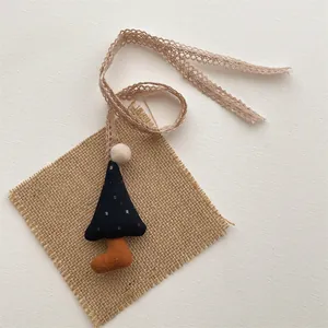 Detail of a handmade navy blue polka dot plush pendant with lace cord and pom-pom