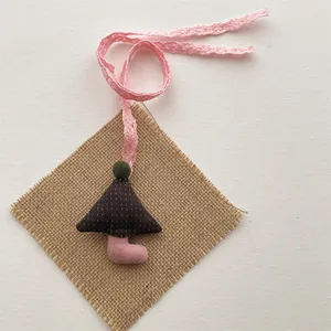Detailed shot of handmade plush mushroom charm with pink lace ribbon and fabric textures