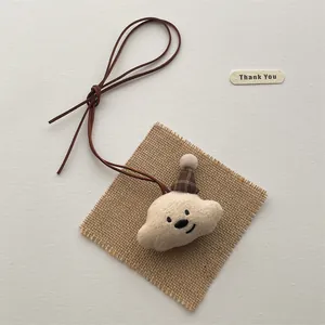 Detail of cloud-shaped plush bear charm with plaid hat and brown faux leather cord