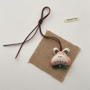 Detail of handmade cloth bunny pendant with embroidery and brown leather cord