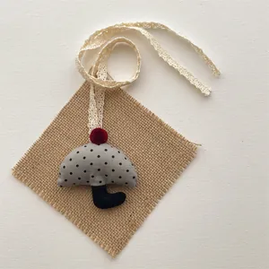 Detail of gray polka dot umbrella pendant with a red pompom and lace ribbon strap