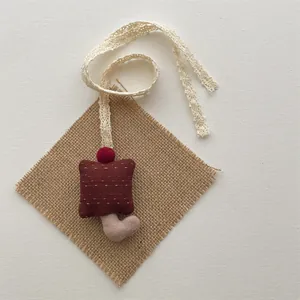 Close-up of handmade mushroom charm with red fabric and delicate lace strap detail