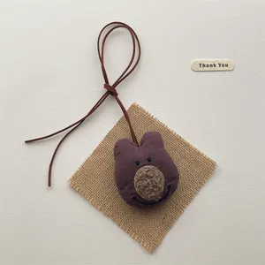 Detailed macro shot of a purple fabric bear charm with soft teddy plush facial accents