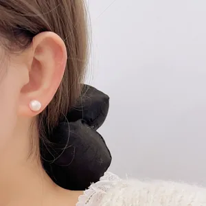 Nahaufnahme des rosa Perlenohrsteckers am Modell mit elegantem Spitzenkragen-Outfit