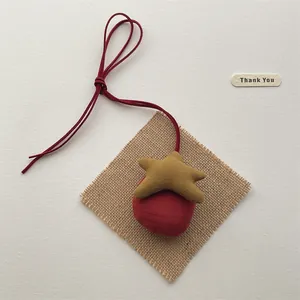 Close-up of a plush fabric star pendant with a red suede bow and handmade texture