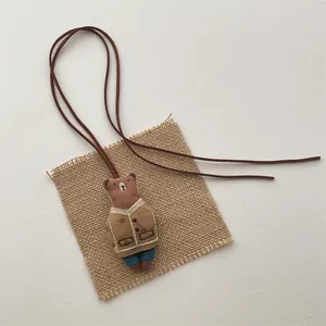 Detailed view of handmade brown bear pendant with embroidery and brown leather cord