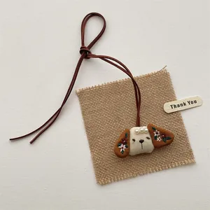 Cute handmade plush puppy charm with floral embroidery and pearl accents on a long cord