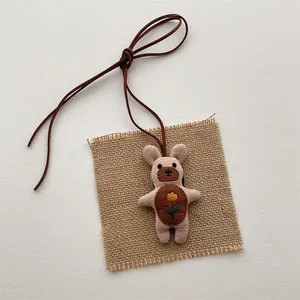 Close-up of a pink fabric cartoon bear plush pendant with embroidered floral detail