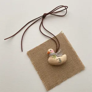 Detail of handmade fabric duck pendant with fringe scarf and leaf embroidery