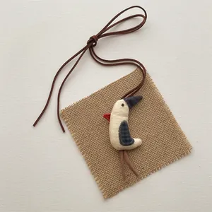 Macro view of a handmade fabric bird charm with rustic stitching and long leather cord