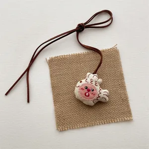 Detailed close-up of a handmade fabric cartoon fish pendant with red embroidery details