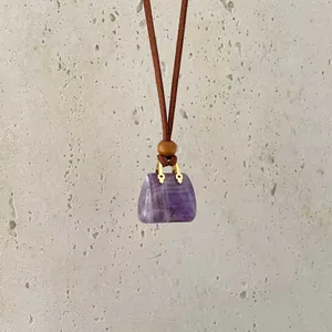 Close-up of a handbag-shaped purple crystal pendant with gold hardware and wood bead