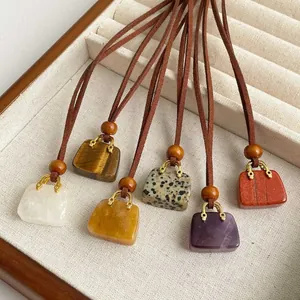 Natural tiger eye stone handbag pendants on leather cords in a wooden jewelry tray