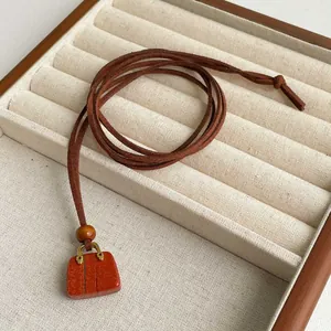 Tiger eye stone handbag pendant necklace with brown suede cord on jewelry display