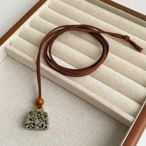 Detailed view of tiger eye stone handbag pendant on beige velvet jewelry display tray
