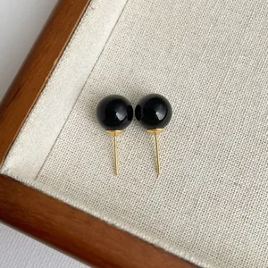 Detailansicht eleganter schwarzer Achat-Ohrstecker auf einem strukturierten Stoffdisplay