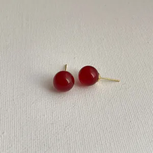 Nahaufnahme minimalistischer roter Achat-Ohrstecker mit polierten goldfarbenen Stiften