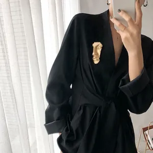 Artistic golden abstract face brooch pinned on a black blazer for a modern fashion look