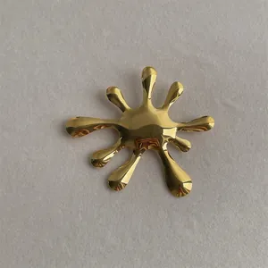 Macro shot of liquid splash shaped golden brooch with polished metallic texture