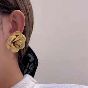 Minimalist fabric rose earrings with gold metal petals on a model, stylish floral ear studs