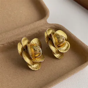 Detailed view of golden 3D rose earring with metallic texture on vintage background